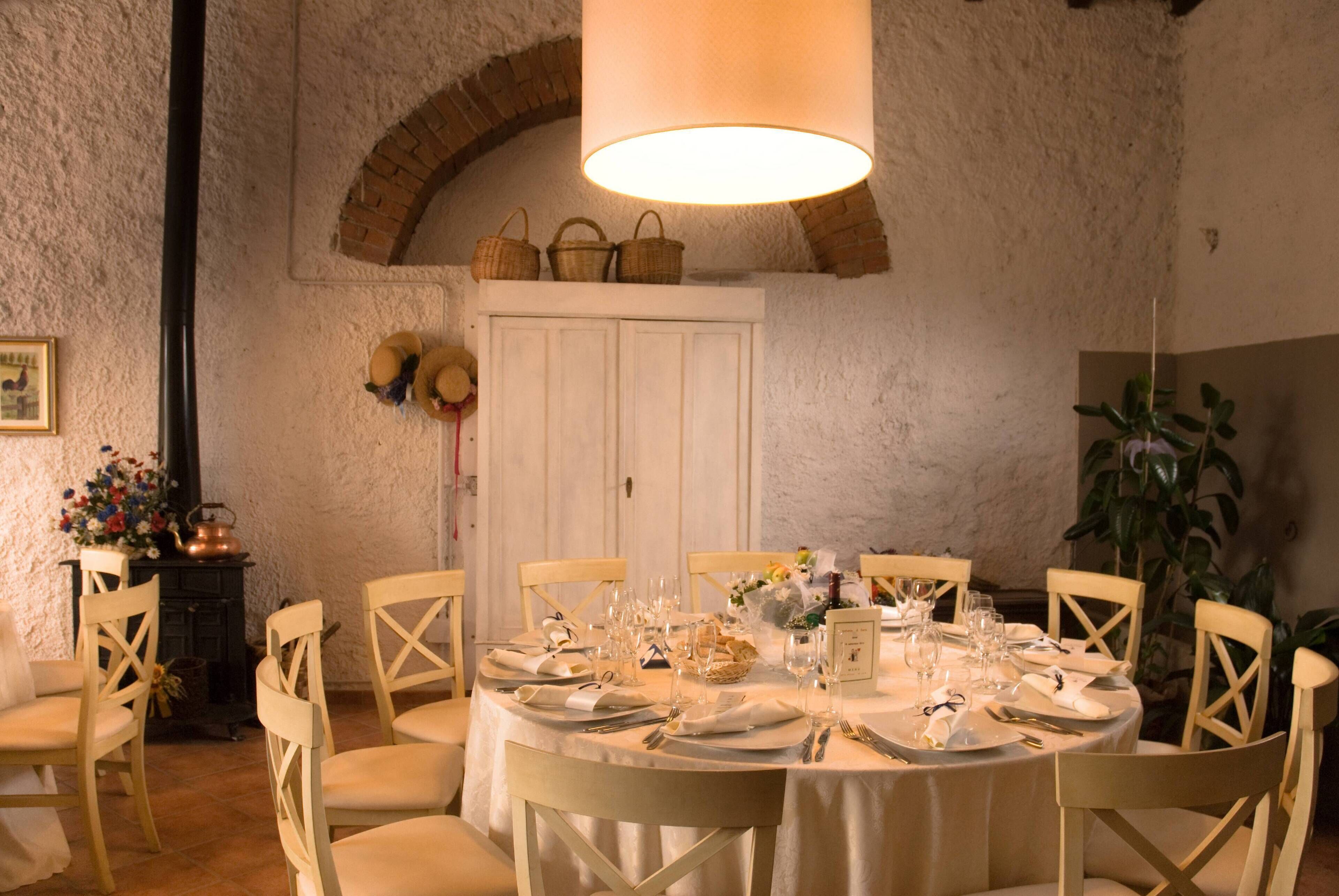 A dining room with a round table set for six, surrounded by wooden chairs.