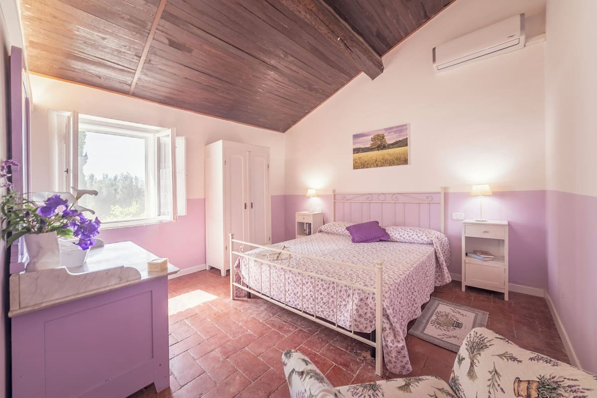 A bedroom with a bed, bedside tables, a dresser, a window, and a ceiling fan.