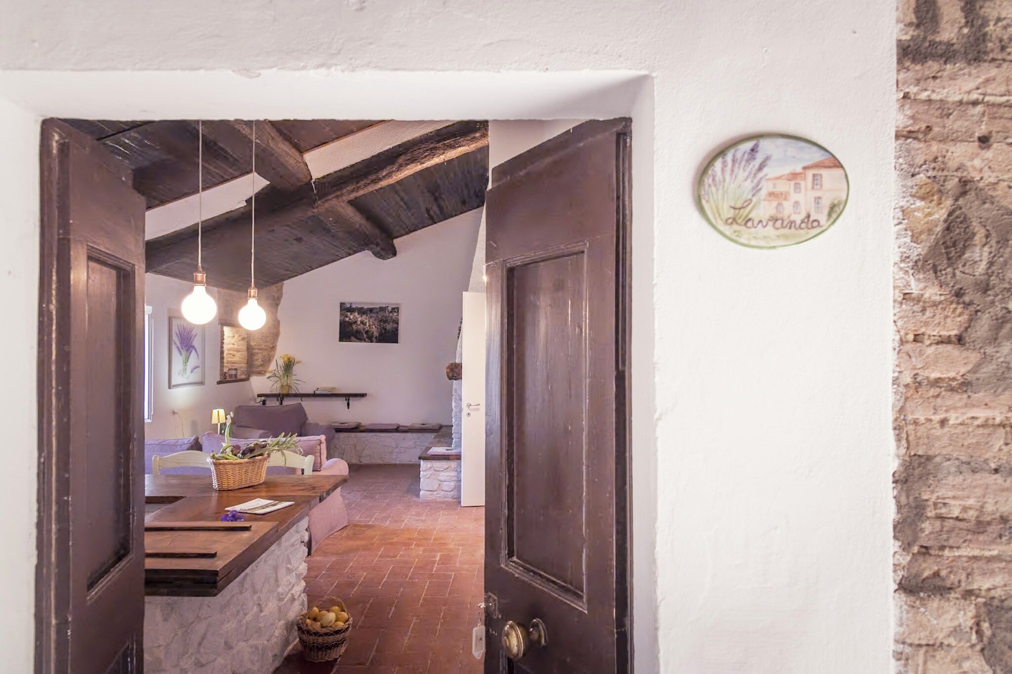 A rustic interior with exposed beams, a stone wall, and a wooden counter with a basket.