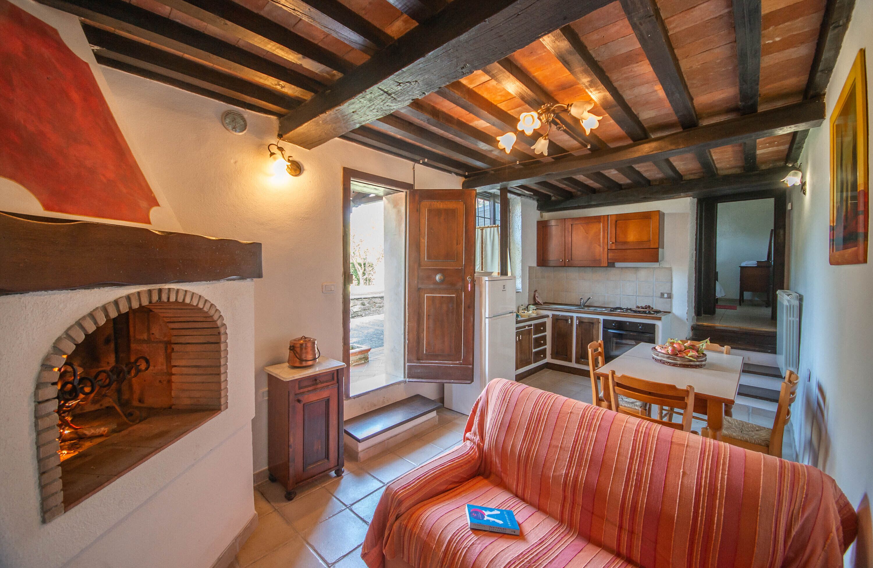 A cozy kitchen with wooden beams, a built-in oven, and a dining area with a striped sofa and a table.