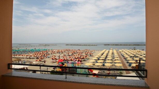 A balcony with a view of a beach with numerous umbrellas and sun loungers. - Hotel Riposo (Gatteo)