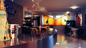 A modern bar area with a counter, a coffee machine, and a television in the background. - Hotel Riposo (Gatteo)
