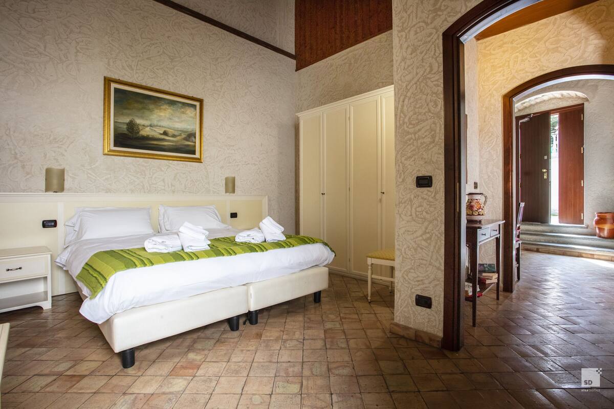 A hotel room with a bed, a wardrobe, a nightstand, and a painting on the wall.