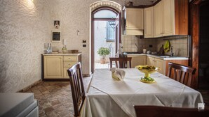 A dining area with a table set for two, a kitchen with wooden cabinets, and a doorway leading outside.