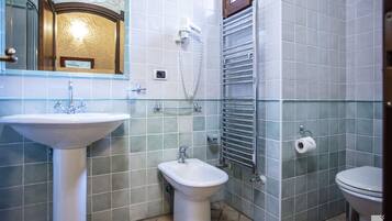 Une salle de bain comprenant un lavabo sur colonne, un bidet, des toilettes et un porte-serviettes.