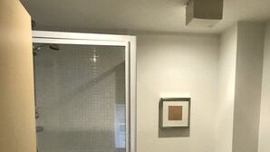 A bathroom with a glass-enclosed shower, a toilet, and a small shelf with toiletries. - Mermaid Bay (Cardiff)