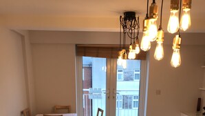 A modern living room with a sofa, a chair, a small table, and a balcony with a railing. - Mermaid Bay (Cardiff)