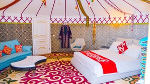 Une pièce comprenant un lit, un canapé, une chaise et un tapis à motifs.