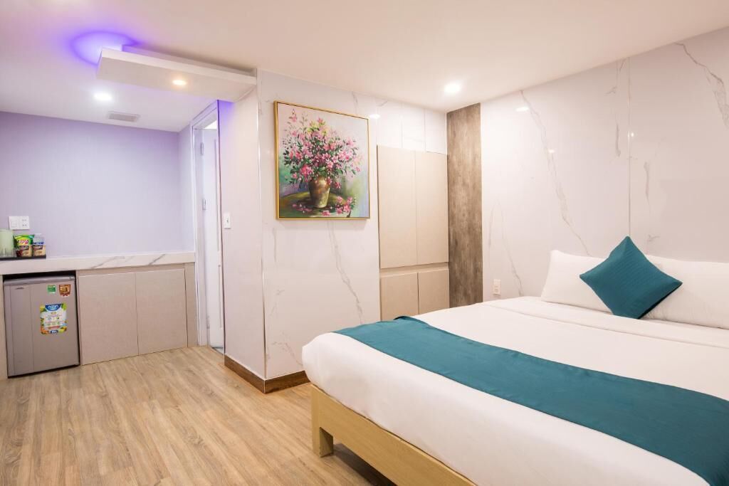 A hotel room with a bed, a small kitchenette, and a bathroom.