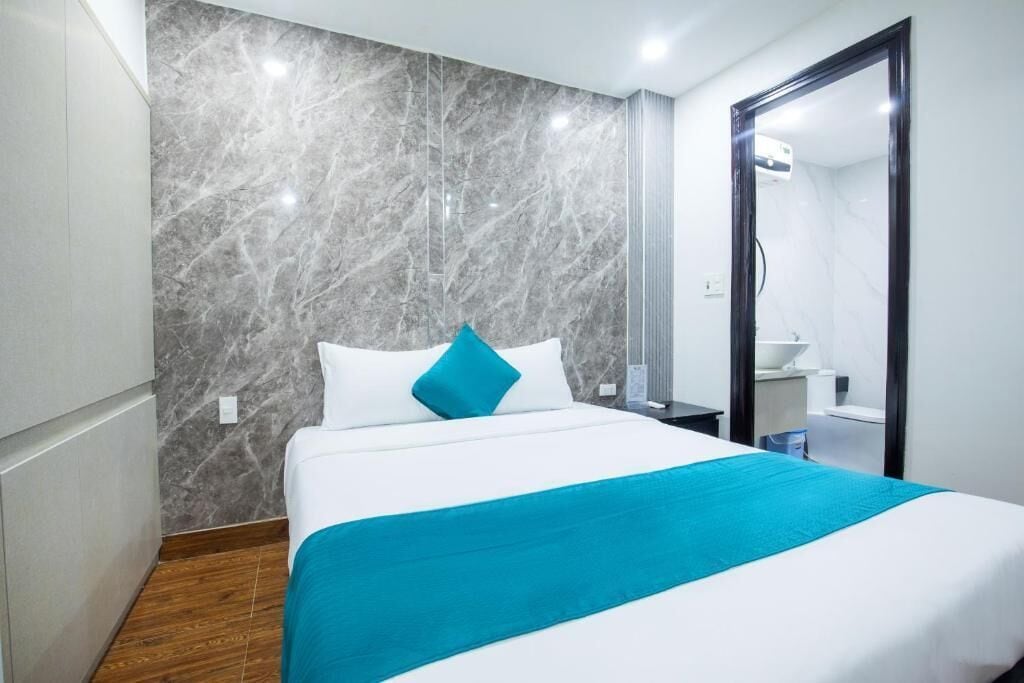 A hotel room with a bed, a bathroom, and a marble wall.