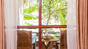 Una habitación con un amplio ventanal, muebles de madera y vistas al exterior con vegetación.