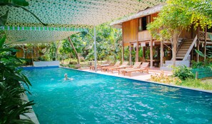 Un área de piscina con sillas de descanso y una persona nadando.