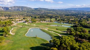 A golf course with a pond, surrounded by trees and hills in the background. - Le Domaine de Provence Country Club (Saumane-de-Vaucluse)