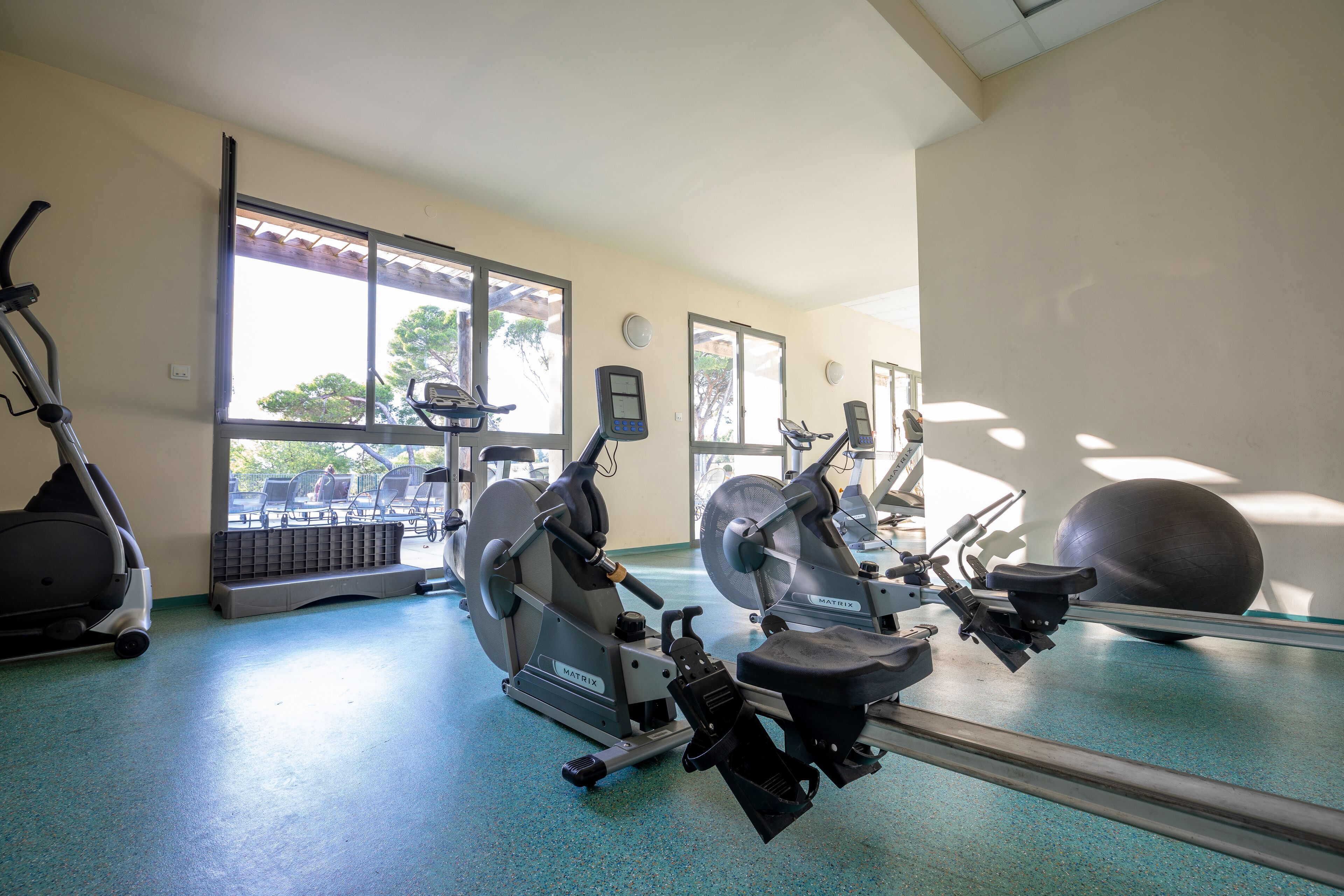 Ein Fitnessraum mit Ergometer, Laufband und Gymbällen.