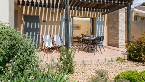 A covered patio area with a stone wall, outdoor seating, and a door leading to an interior space. - Le Domaine de Provence Country Club (Saumane-de-Vaucluse)