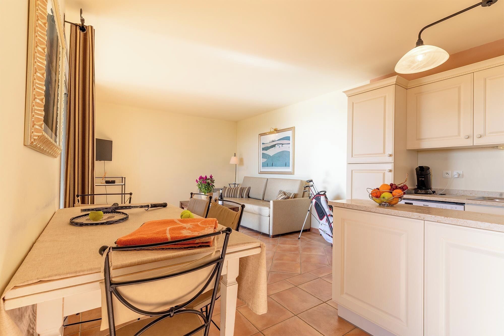 Un espacio habitable compacto con comedor, kitchenette y un sofá al fondo.