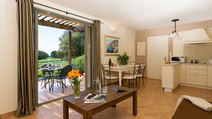 A modern kitchen with white cabinets, a microwave, and a dining area with a table and chairs. - Le Domaine de Provence Country Club (Saumane-de-Vaucluse)