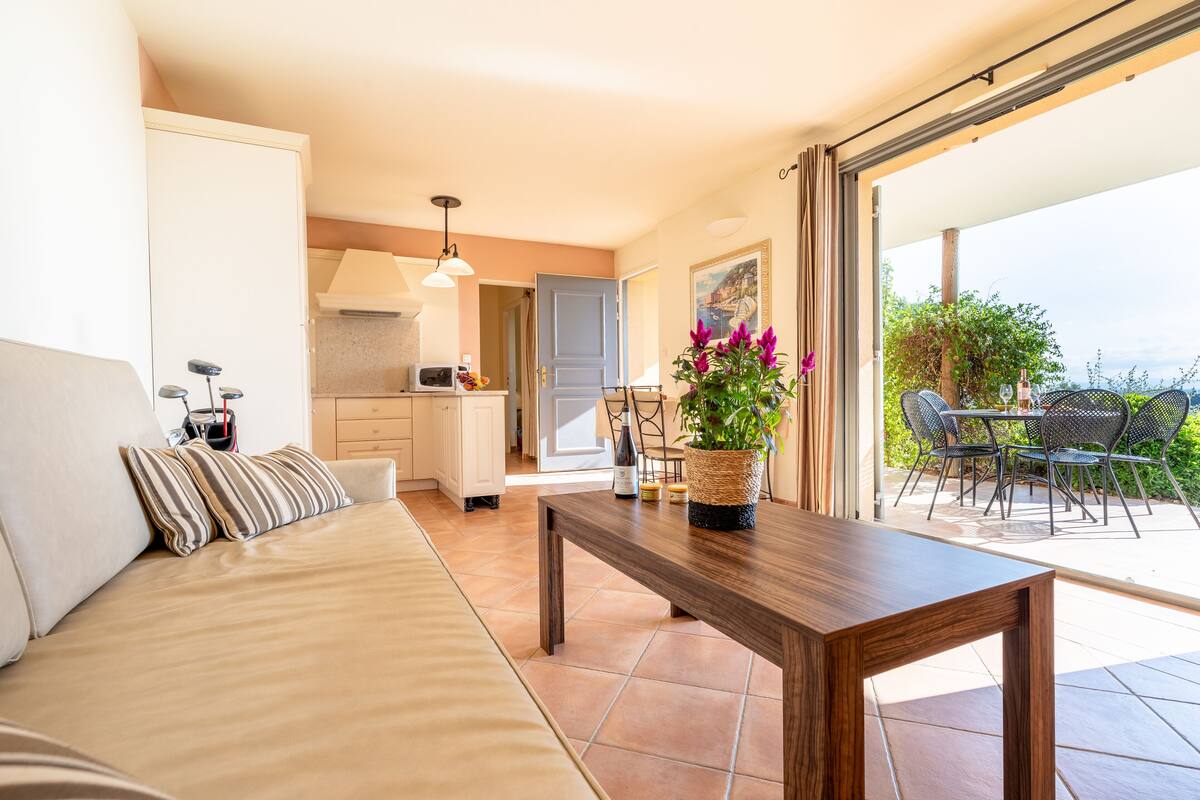 A modern living room with a sofa, a wooden coffee table, and a view of the outdoor patio area.