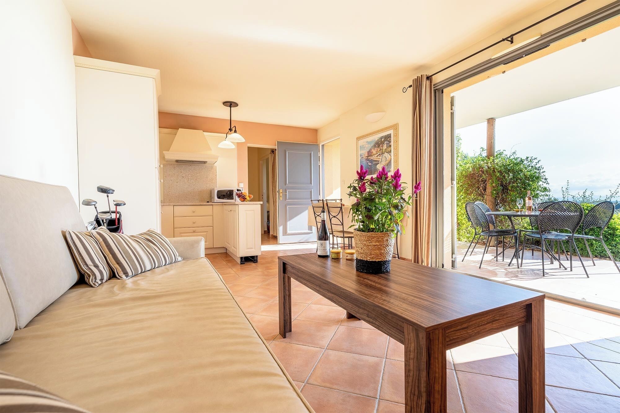 A living room with a sofa, a wooden coffee table, and a view of the outdoor patio with chairs and a table.