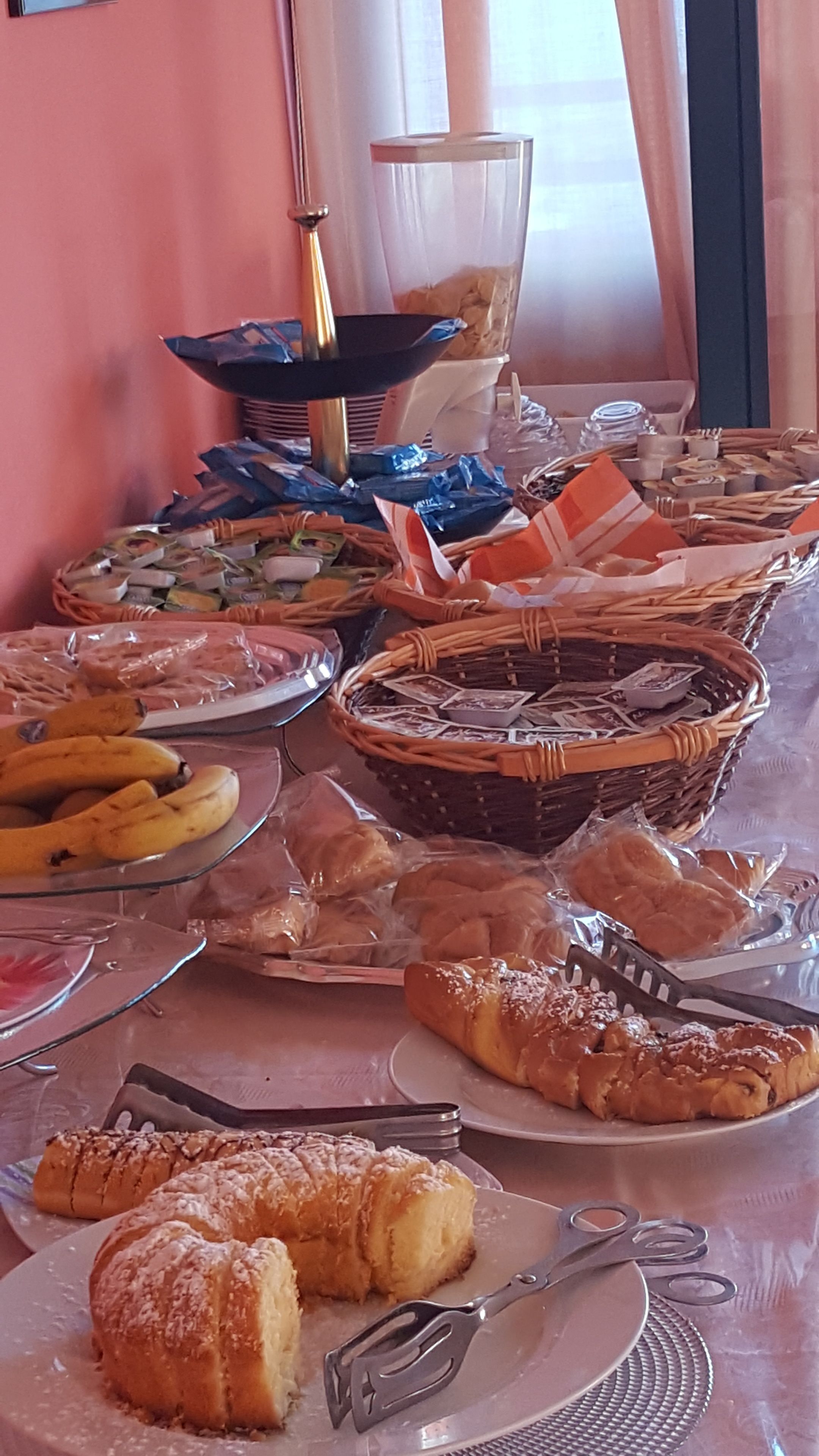 A buffet table with various food items including bread, pastries, and fruits.