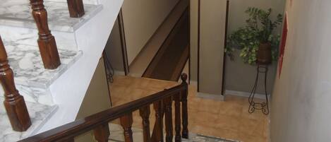 A marble staircase with wooden balusters and a beige wall.