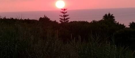 A sunset over a coastal landscape with a road in the foreground.