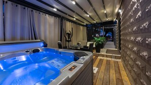 Un espace de bien-être comprenant un jacuzzi, des sièges et un mur en pierre.