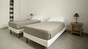 Een slaapkamer met twee bedden, een nachtkastje met een lamp en een inbouwkast.