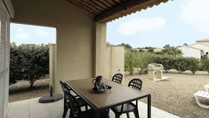 Een terras met een tafel, stoelen, een barbecue en comfortabele loungestoelen.