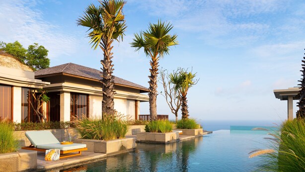A modern house with an infinity pool, palm trees, and a lounge chair. - Six Senses Bali (Pecatu)