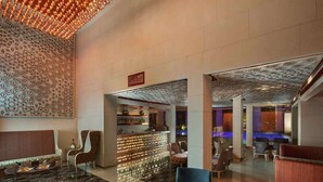 A spacious lobby with a bar area, seating arrangements, and a pool area visible in the background. - Sarovar Premiere Jaipur (Jaipur)