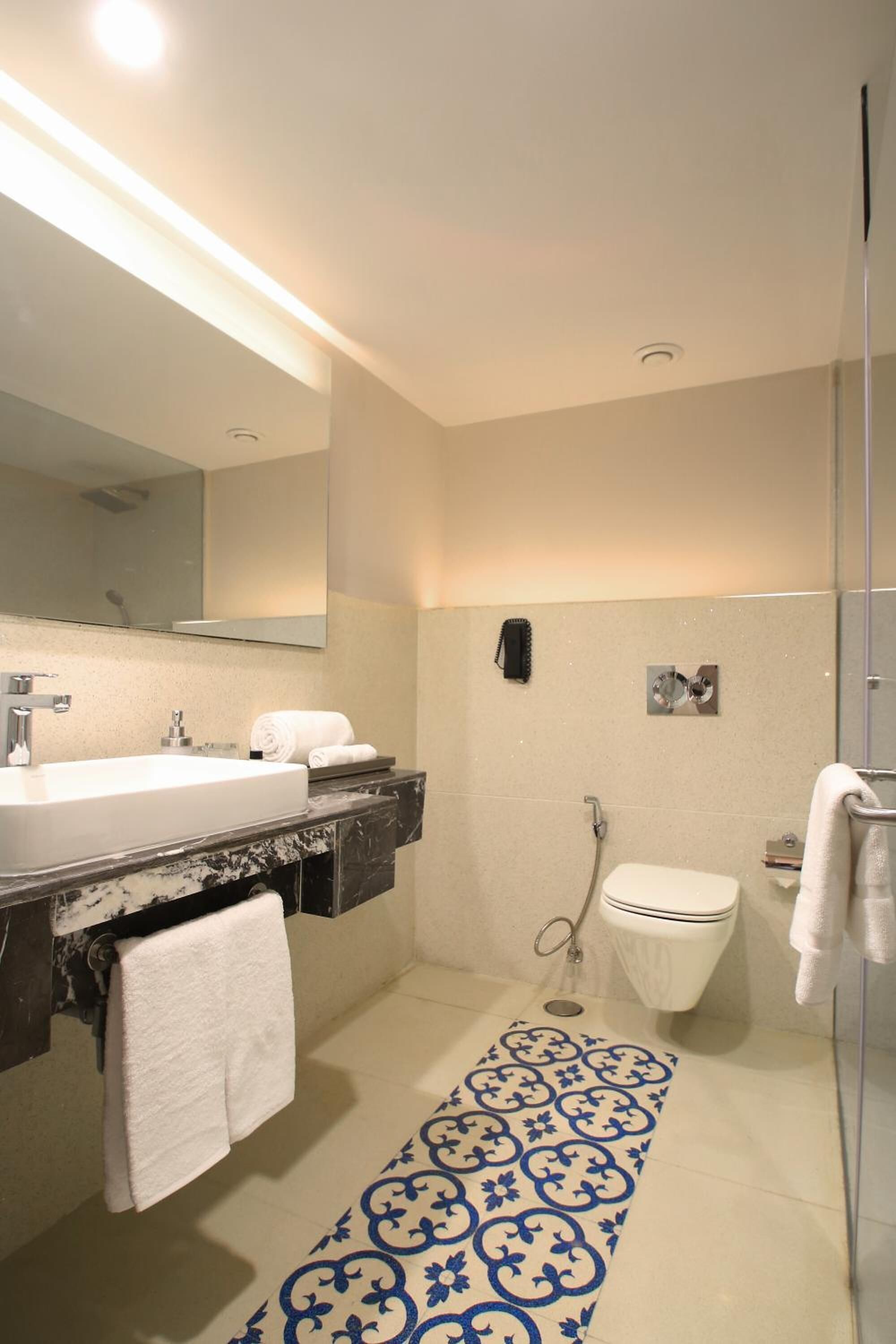 Une salle de bain moderne avec un grand miroir, deux lavabos, des toilettes et une douche.