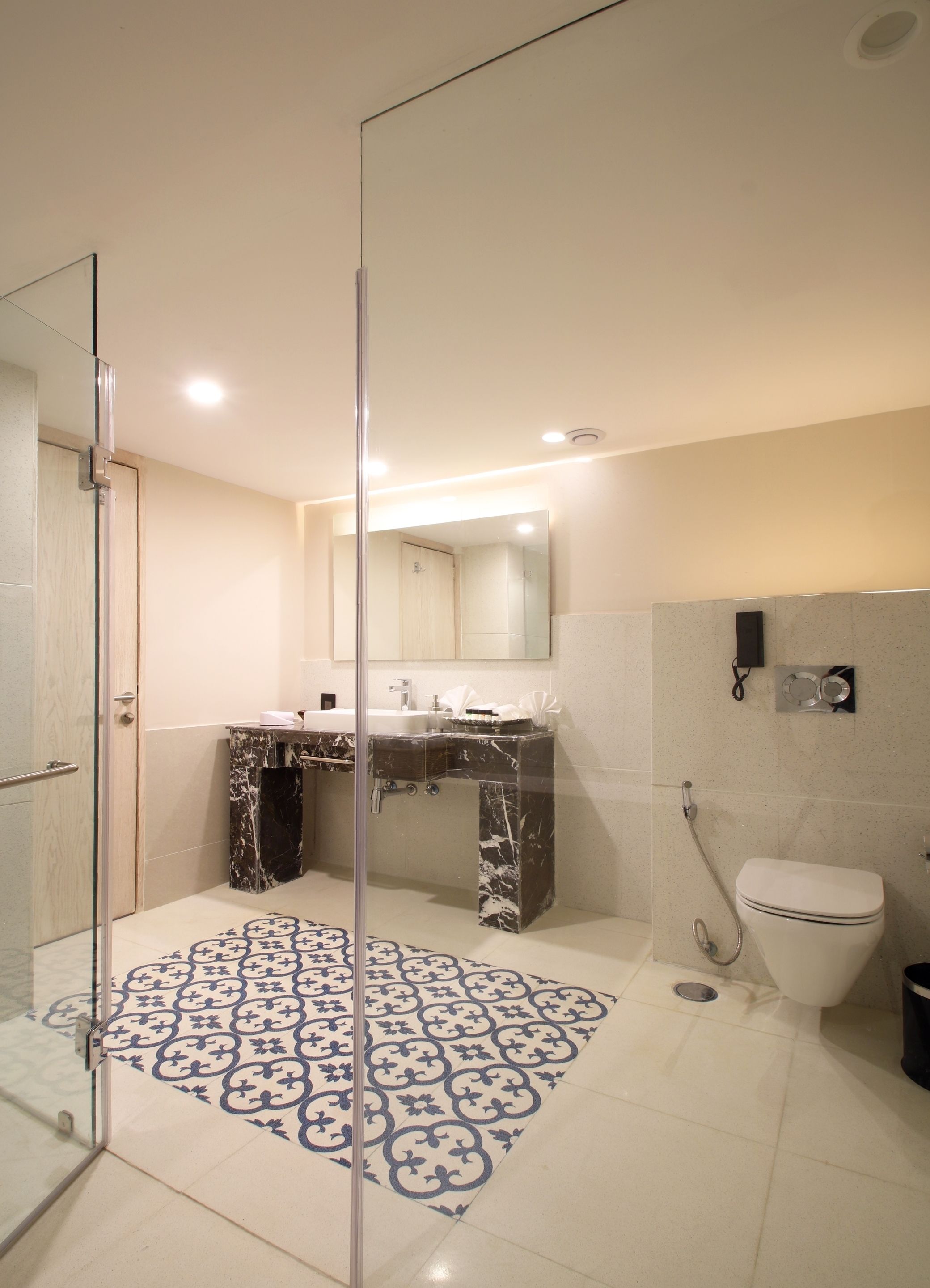 Um banheiro moderno com box de vidro, pia de mármore e vaso sanitário.