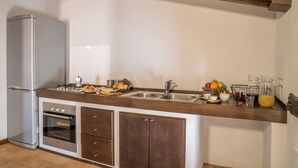 A compact kitchen with a built-in oven, a stainless steel refrigerator, and a wooden countertop. - Plaium Montis (Salerno)