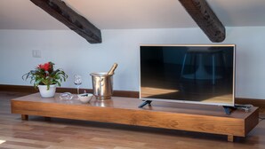 A modern living room with a wooden TV stand, a potted plant, a wine glass, and a metal pot. - Plaium Montis (Salerno)