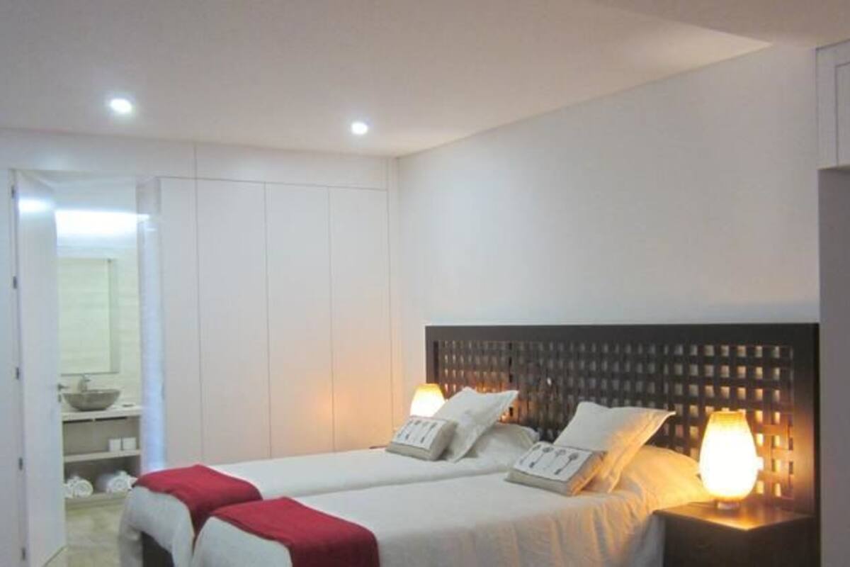 A hotel room with two beds, a large mirror, and a bedside table with a lamp.