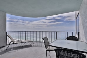 Enjoy the ocean view from this balcony with comfortable lounge seating and a table.