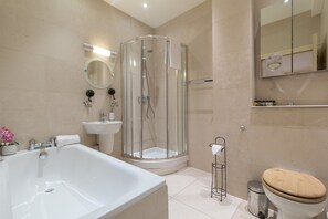 A modern bathroom with a glass-enclosed shower, a freestanding bathtub, a toilet, and a sink.