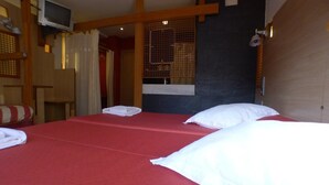 A hotel room with a bed, a television, and a window with a curtain. - Hotel Castillo del Alba (Somiedo)