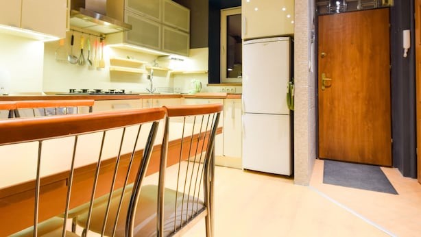 A modern kitchen with wooden beams, a refrigerator, and a bar area with metal chairs. - ShortStayPoland Leszno - B53 (Warsaw)