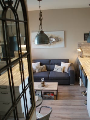 Un salon chaleureux avec un canapé gris foncé, une table basse et une suspension.