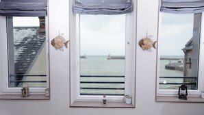 Ein Zimmer mit drei Fenstern und Meerblick, mit Leuchtturm und Steg.