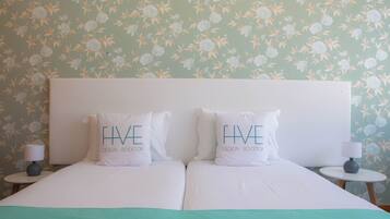 Una cama doble con dos almohadas, una mesita de noche, una lámpara y un papel tapiz con motivos florales.