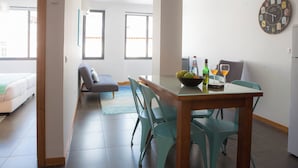A modern living space with a dining area, a sofa, and a large wall clock.