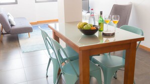 A dining area with a table set for two, featuring a bowl of fruit, a bottle of water, and two glasses of a yellow beverage. - Five Design Rooftop by Storytellers (Funchal)