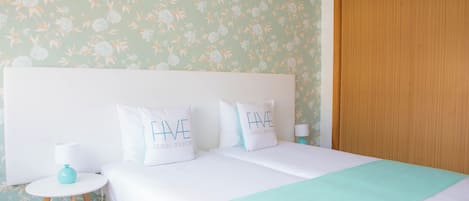 A hotel room with a bed, two pillows, a bedside table, a lamp, and a wooden wardrobe.