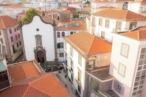 A narrow street with buildings featuring red-tiled roofs and white facades. - Five Design Rooftop by Storytellers (Funchal)