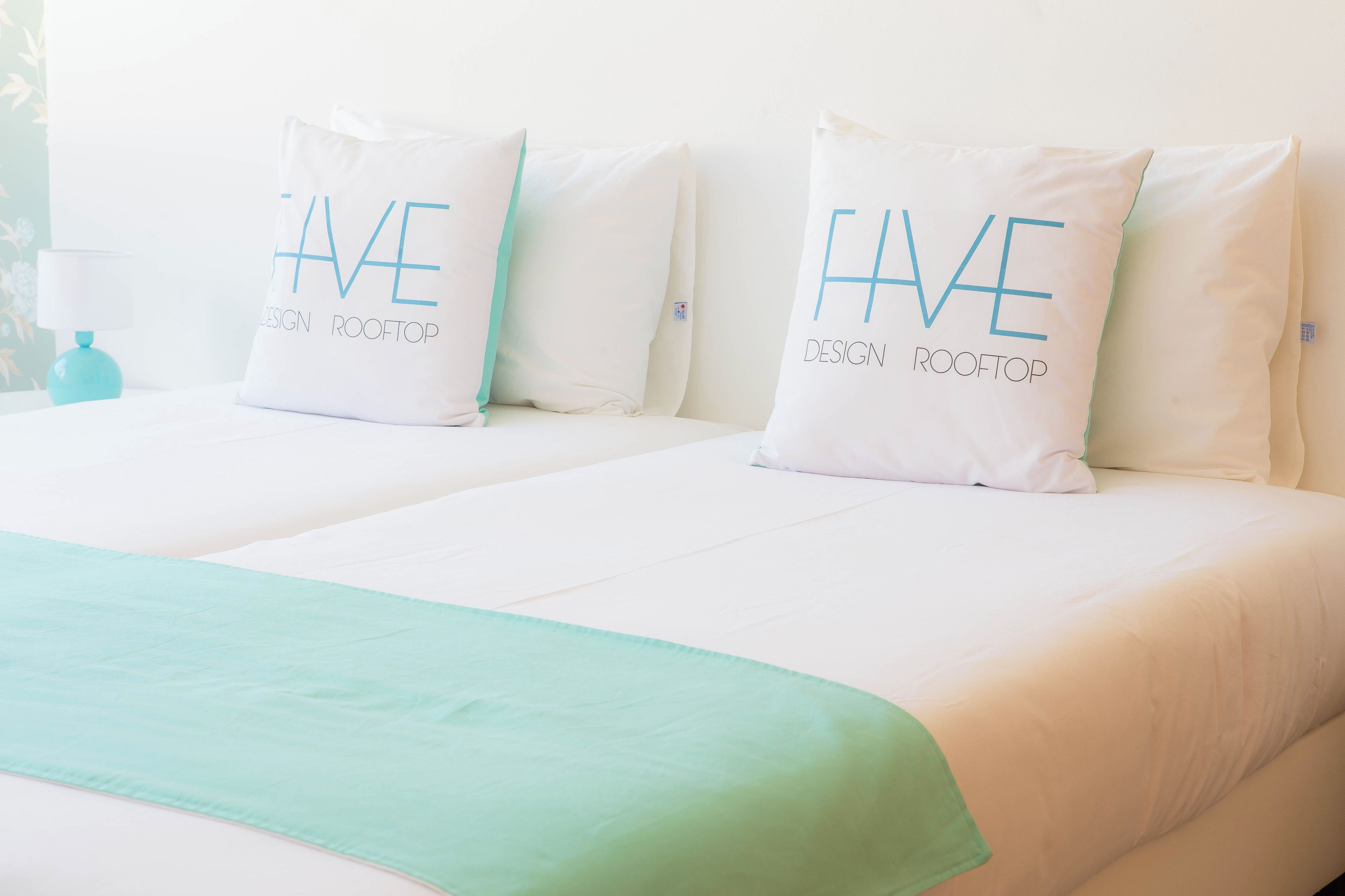 A hotel room with two beds, each with a pillow that reads "HAVE DESIGN ROOFTOP".