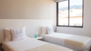 A hotel room with two beds, each with a pillow that reads "HAVE DESIGN ROOFING."