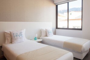 Ein Hotelzimmer mit zwei Betten, jedes mit einem Kopfkissen, auf dem 'HAVE DESIGN ROOFING' steht.